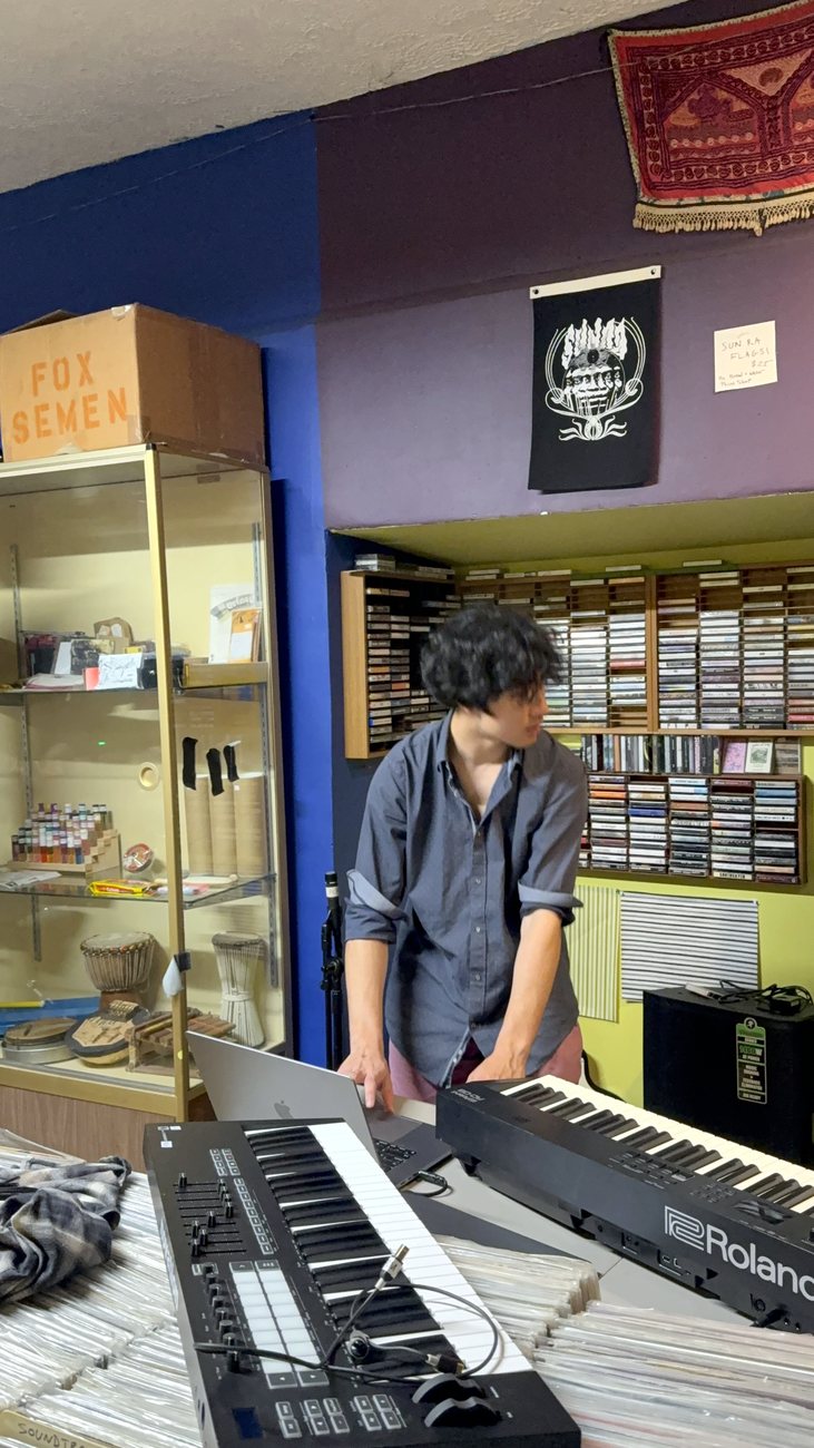 Warren performing with synthesizers and keyboards in a dim studio space