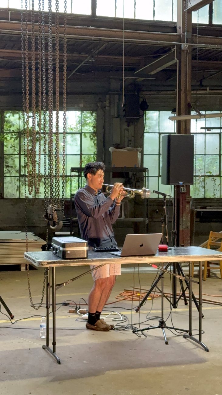 Warren performing trumpet through electronic processing in a warehouse space
