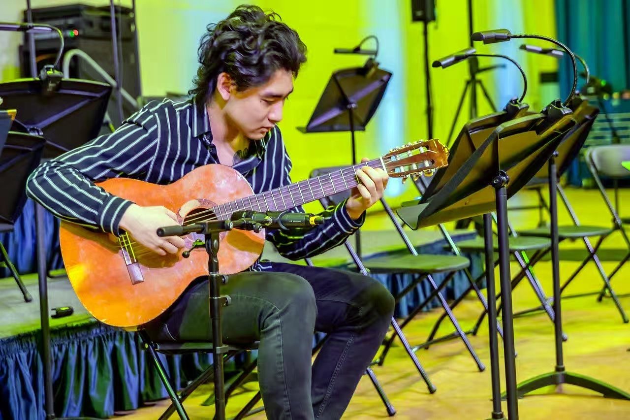 Warren performing on classical guitar, focused on the fretboard